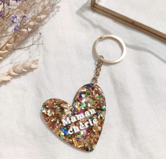 Porte clés "Maman chérie"

- Forme cœur

- Couleur: pailleté, multicolore

- Résine

Mile et Mila

Les accessoires ne sont ni repris, ni échangés